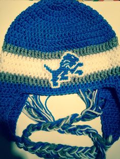 a blue and white crocheted hat with a lion on it's side