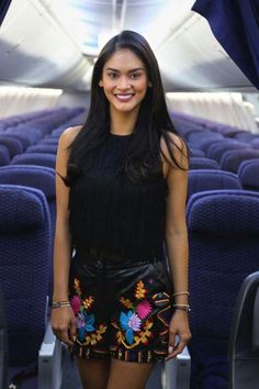 a woman standing on an airplane with her legs crossed and wearing high heeled boots