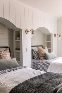 two twin beds in a bedroom with white walls and wood paneled headboards,