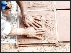 a man is working with clay on a tile floor in front of a brick wall