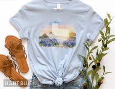 Looking for a shirt that captures the beauty of Texas bluebonnets? Look no further than this stunning watercolor design, featuring the iconic flowers in a dreamy, ethereal style. But that's not all: the bluebonnets are set against the outline of the Lone Star State itself, making this shirt the perfect way to show your love for the great state of Texas. Whether you're a native Texan or just a fan of the state's natural beauty, this shirt is sure to become a favorite in your wardrobe. Made with h Blue Watercolor Print Tops For Spring, Blue Watercolor Print Top For Spring, Blue Short Sleeve Tops With Watercolor Print, Blue Short Sleeve Top With Watercolor Print, Blue Custom Print T-shirt For Spring, Texas Themed Gifts, Air Force Families, Texas Shirt, Texas Bluebonnets