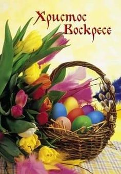 a basket filled with lots of colorful flowers next to an easter egg on top of a table