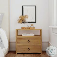 a nightstand with two drawers and a framed photograph on the wall above it next to a bed