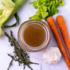 carrots, celery and other vegetables on a white counter top with a jar of liquid