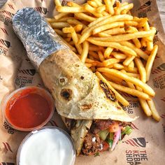 a burrito and french fries with ketchup are on the wrapper next to each other