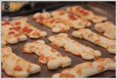 small pizzas are arranged in the shape of crosses on a baking sheet, ready to be cooked