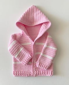 a crocheted pink sweater with white stripes on the sleeves and hood is shown