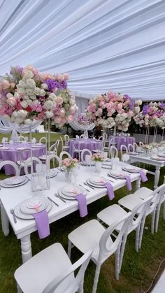 a table set up with white chairs and purple napkins on it for a wedding reception