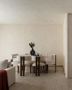 a living room with a couch, table and chairs next to a wall that has a vase on it