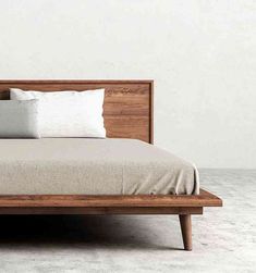 a bed with two pillows on top of it and a wooden frame in the middle