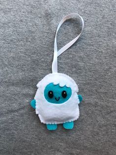 a blue and white stuffed animal ornament hanging from a string on a gray surface