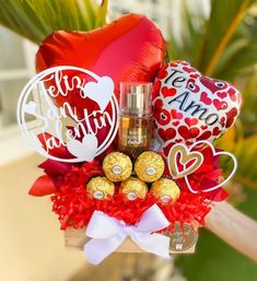 a valentine's day gift basket with chocolates, candy and balloons in it