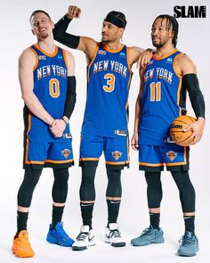 three basketball players pose for a photo in their new york jersey shirts and shorts, with one holding a basketball