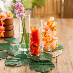 three vases filled with colorful flowers on top of a wooden table next to plants