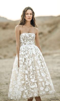 a woman standing in the desert wearing a strapless dress with flowers on it's waist