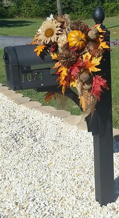 a mailbox decorated with fall leaves and sunflowers is sitting in the gravel