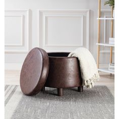 a brown ottoman sitting on top of a rug next to a wooden chair with a white throw pillow