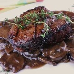 steak with mushrooms and gravy on a white plate