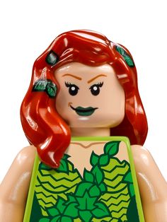 a close up of a lego figure with red hair and green dress on it's chest