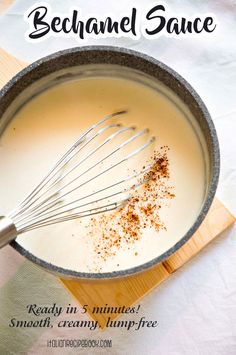 a whisk in a pan filled with milk and spices on top of a wooden cutting board