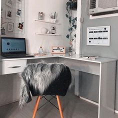 a desk with a laptop on it and a furry chair in front of the desk