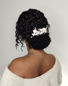 the back of a woman's head with curly hair and flowers in her hair