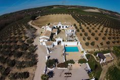 an aerial view of a large house in the middle of a field with olive trees