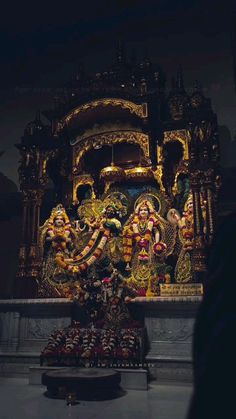 an idol is displayed in front of a dark room with people standing around and looking at it