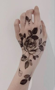 a woman's arm with black and white flowers on it, holding her hand in the air