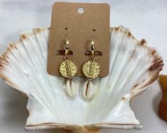 Elevate your beach style with these stunning Hammered Disc and Cowrie Shell Earrings. This beautiful pair is handcrafted with gold plated brass disc beads and natural cowrie shells, making them versatile enough to wear every day and suitable for any occasion. The lightweight design and easy to wear leverback hoops make them a comfortable choice for all-day wear. The earrings measure 5 cm in length, with the 24K gold plated hoops measuring 15 mm in diameter and 1.6 cm in length. These statement e Gold Beachy Jewelry For Beach Party, Handmade Hoop Earrings For Summer Vacation, Gold Drop Earrings For Vacation, Summer Beach Dangle Hoop Earrings, Summer Vacation Dangle Hoop Earrings, Gold Round Earrings For Vacation, Adjustable Gold Earrings For Summer, Gold Jewelry For Summer Beach, Gold Jewelry For Summer Vacation