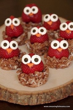 some food is sitting on top of a wooden plate with strawberries and googly eyes