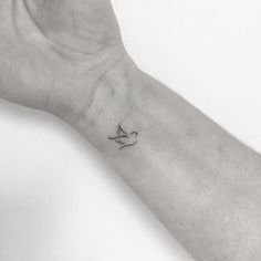 a person's arm with a small bird tattoo on the left side of their wrist