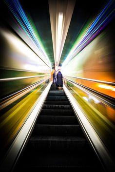 an escalator with people standing on it and moving down the stairs at night