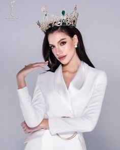 a woman wearing a white suit with a tiara on her head and hands behind her back