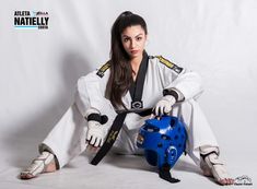 a woman sitting on the ground with a blue object in her hand and wearing black gloves