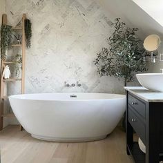 a large white bath tub sitting under a bathroom window next to a sink and mirror