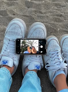 a person taking a selfie with their cell phone on the sand at the beach