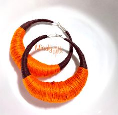 two orange and brown hoop earrings on a white plate