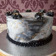 a black and gold decorated cake sitting on top of a wooden table next to a wall