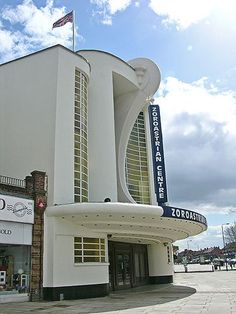 a large white building sitting on the side of a road next to a tall flag pole