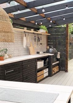 an outdoor kitchen with lots of wood and plants on the counter top, under a pergolated roof