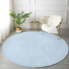 a white chair sitting on top of a blue rug next to a potted plant