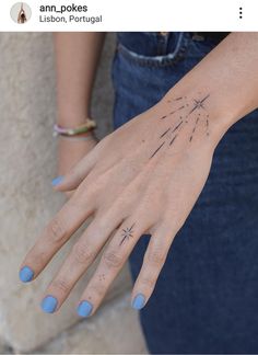 a woman's hand with blue nail polish and stars tattoo on her left wrist