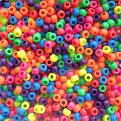 there are many different colored beads on the table and in the background is a pile of them