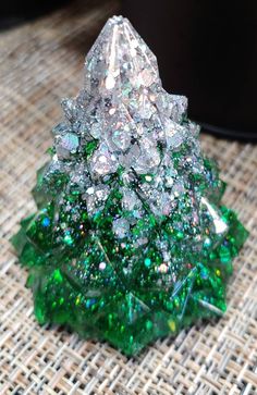 a green and white christmas tree made out of glass on top of a woven table cloth