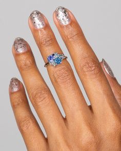 a close up of a person's hand with silver and blue manicures