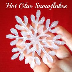 a hand holding a snowflake made out of white plastic beads on a red background with the words hot glue snowflakes