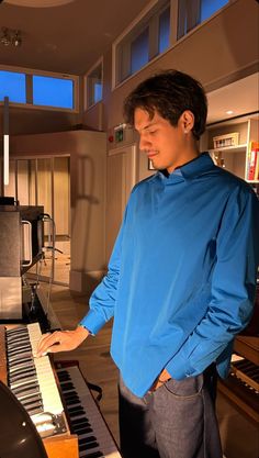 a young man standing in front of a piano and looking at the keys on it