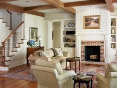 a living room filled with furniture and a fire place in front of a stair case