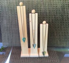 three pieces of wood with necklaces in them on a counter top next to a tile wall